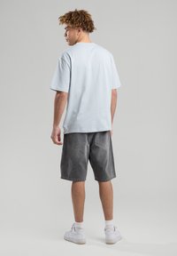 Light blue cotton t-shirt with short sleeves, paired with gray denim shorts. White sneakers complete the look. Simple design and relaxed fit.