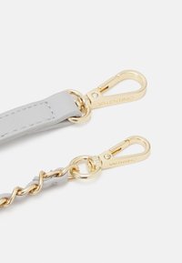 Szürke bőrszíj aranyszínű fémszerelvényekkel, karabinerzárral és láncszemes részletekkel, sima textúrával és dombornyomott logóval.