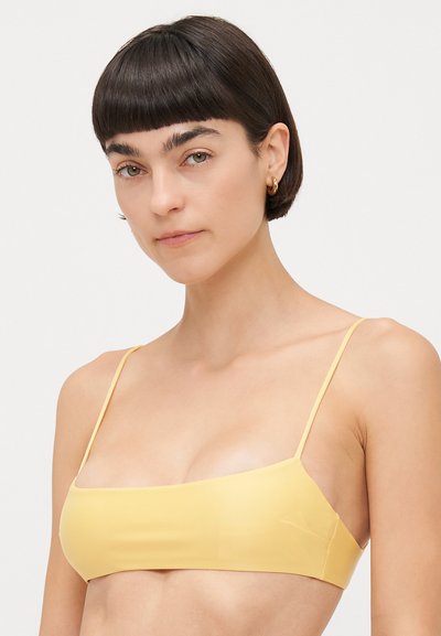 Yellow bikini top with thin straps, smooth texture, rectangular shape, minimalistic design, and no visible hardware or patterns.