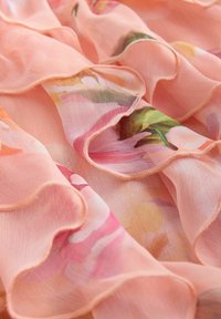 Leichter, rosa Chiffonstoff mit Blumenmustern. Verfügt über weiche, geraffte Kanten und eine glatte Textur, die ein zartes Erscheinungsbild erzeugt.