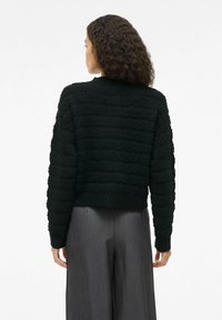 Zwarte textuur ge cropped trui met een ribbelzoom en lange mouwen, met een verhoogd patroon detail op de achterkant.