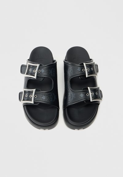 Sorte slidesandaler med to justerbare spænder, tekstureret syntetisk materiale, flad sål og indgraveret logodetalje på remmene.