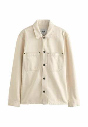 Veste en denim beige avec un col pointu, des manches longues, deux poches poitrine et des boutons noirs. Texture lisse avec des coutures renforcées.