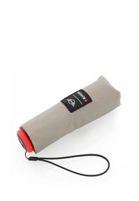 Beige compacte paraplu met een rode handgreep, een zwart etiket met witte graphics en een zwarte polsband voor gemakkelijk dragen.