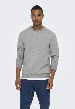 Gray crewneck sweatshirt made of soft fabric, featuring long sleeves and ribbed cuffs, paired with blue denim jeans.