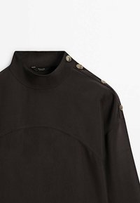 Top nero ad altezza alta con bottoni dorati sulla spalla, tessuto liscio con design strutturato e dettaglio della cucitura curva sul petto.