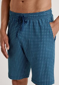 Heren zwemshorts in donkerblauw met een vierkant patroon in lichter blauw. Heeft een elastische tailleband met trekkoord en zijzakken.