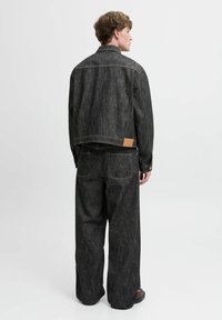 Must  denim jakket ja laiad püksid, millel on tekstuuriline viimistlus, kontrasteeriv õmblus ja nahast tagaplaat jakil.