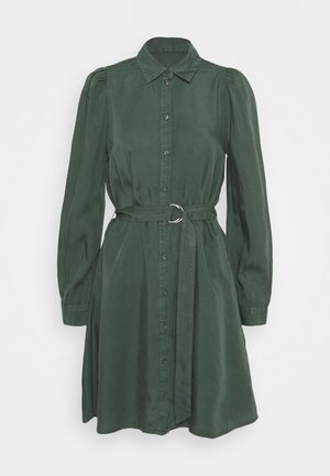 Vestito camicia verde scuro a maniche lunghe con chiusura frontale con bottoni, vita arricciata, spalle a sbuffo, cintura larga con fibbia ad anello in metallo e colletto.