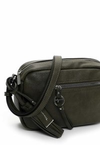 Zelená kožená crossbody taška se zipovým uzavřením, nastavitelným popruhem, vnější kapsou na zip a detailními akcenty. Textura je hladká s jemným leskem.