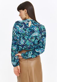 Bluzka z długim rękawem w granatowym kolorze z kolorowym wzorem paisley. Posiada wycięcie na plecach, elastyczne mankiety i lekko cropped krój.