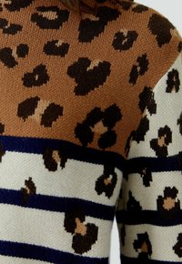 Pull en tricot avec un design en blocs de couleurs, comportant des rayures marron, crème et bleu marine, décoré de taches de léopard de différentes tailles. Texture douce.