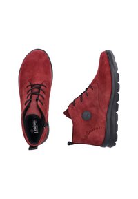 Bottines en daim rouge avec semelle en caoutchouc noire, présentant des lacets, une fermeture éclair sur le côté et un détail de logo circulaire sur le côté extérieur.