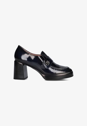 Navy patenten leren loafers met blokhak, een ronde neus, een decoratieve riem en een cirkelvormige metalen accent op de riem.
