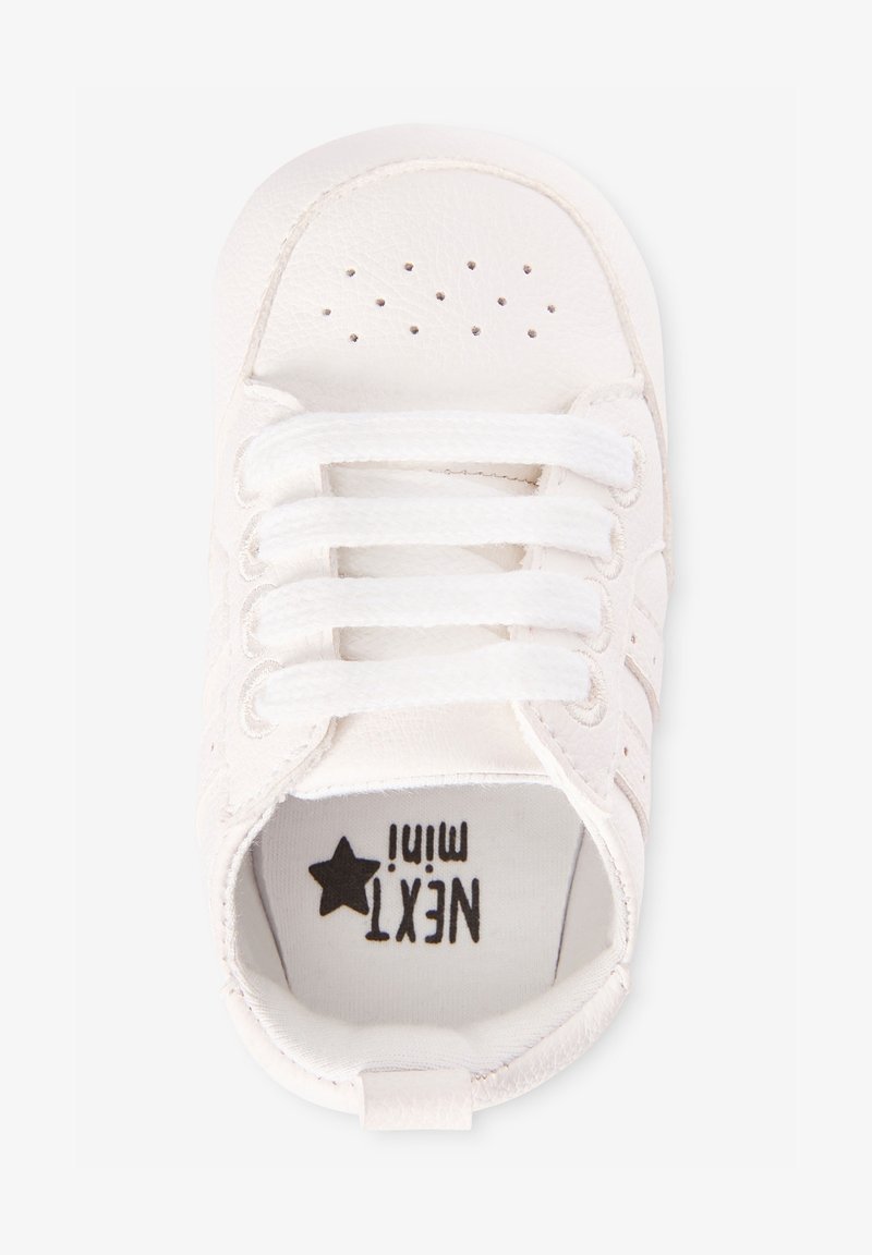 Basket bébé blanche avec lacets, perforations près des orteils et logo "NEXT mini" avec une étoile imprimée à l'intérieur.