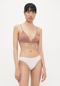 Lichtbruine bralette met kantafwerking en verstelbare bandjes, gecombineerd met lichtroze naadloze bikini slipjes. Gladde textuur, eenvoudig ontwerp.