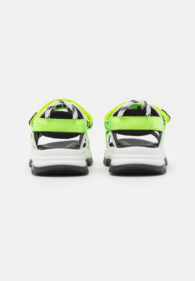Sandálias verdes neon com detalhes pretos, apresentando um design de várias correias, correias ajustáveis no tornozelo e uma sola branca espessa. Forro interior texturizado.