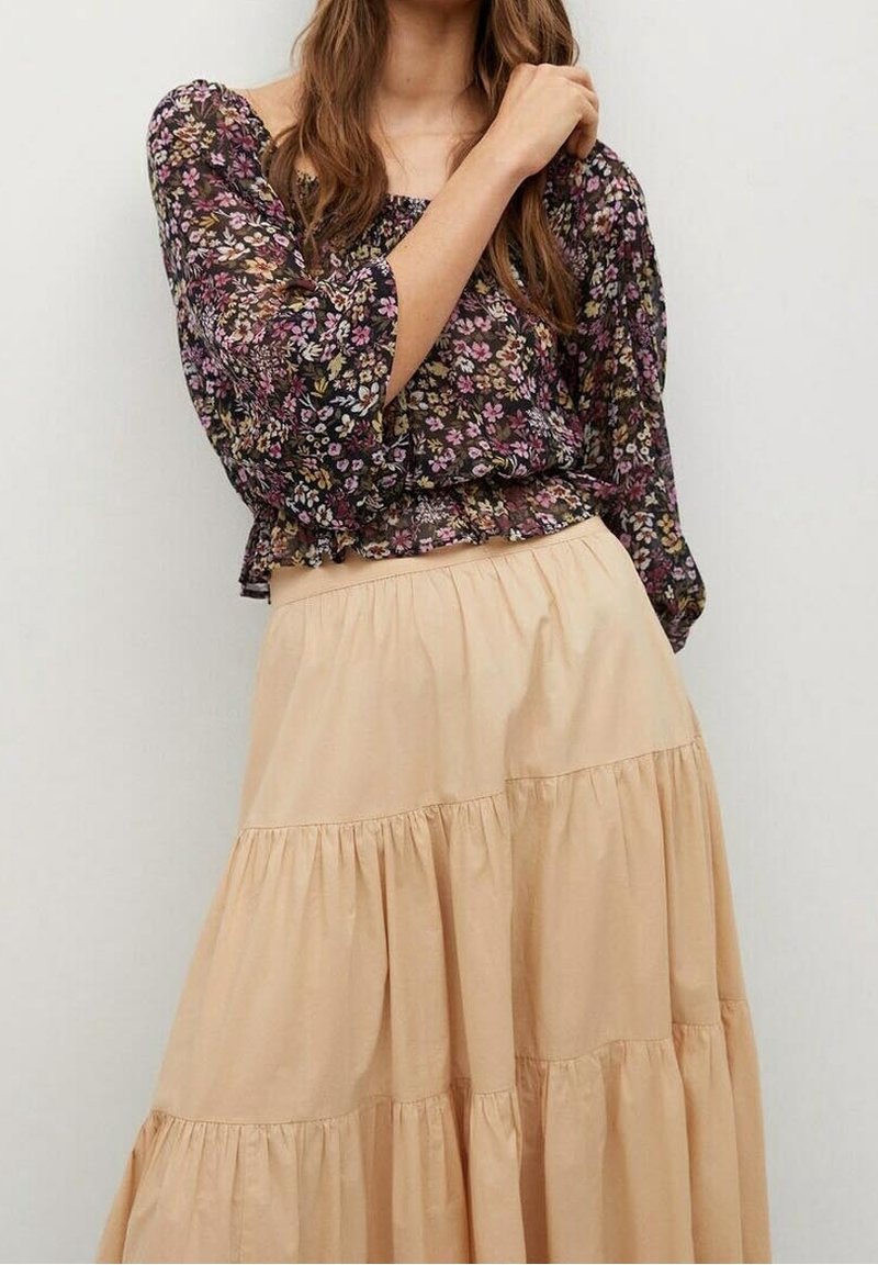 Kwiatowy, czarny krótki top z bufkami i falbaną u dołu, połączony z beżową, warstwową spódnicą do kostek uszytą z miękkiego materiału.