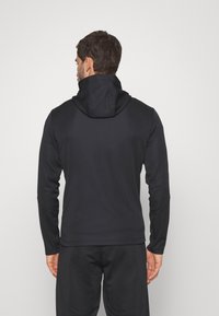 Zwarte hoodie van soepel, rekbaar materiaal, met een hoge kraag en een aansluitend ontwerp. De achterkant heeft een naadloze uitstraling met minimale details.