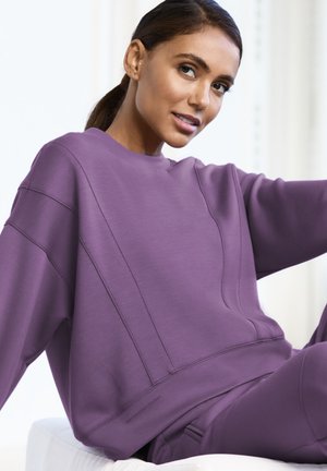 Lila Sweatshirt in lässiger Passform, mit Nahtdetails und Rundhalsausschnitt. Weicher Stoff mit glatter Textur und minimalen Akzenten.