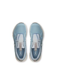 Baskets de sport bleu clair avec un tissu en maille, des accents blancs, des lacets élastiques et un logo sur la languette, présentant une semelle ronde et rembourrée.