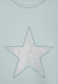 Svetlo modra majica s kapuco z velikim srebrnim motivom zvezde s teksturiranim zaključkom, obdanjem majhnih črnih žebljev na robovih.