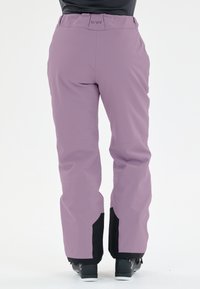 Lila skidbyxor med en slät textur, featuring svarta detaljer vid nederkanten och logotypdetaljer vid midjan. Skräddarsydd passform för rörelsefrihet.