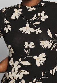 Czarna bluzka w kwiatowy wzór, na której znajdują się kremowe kwiaty z zielonymi akcentami; wykonana z elastycznego materiału, zaprojektowana z wysokim dekoltem.
