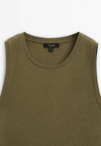 Débardeur côtelé vert en tissu doux. Il présente un col rond et un design sans manches, avec une étiquette d'entretien visible à l'intérieur.