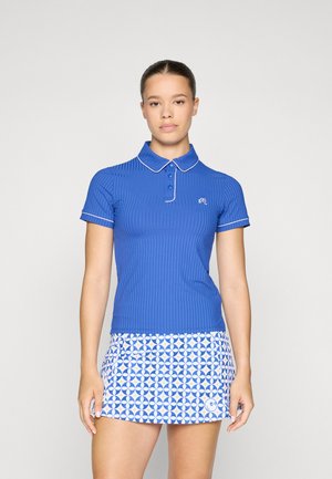Blue ribbed polo shirt with a white collar and trim, paired with a blue and white patterned skort featuring circular designs.