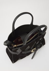 Borsa nera con un esterno in suede testurizzato e dettagli in pelle liscia. Presenta due manici, una chiusura con cerniera e una tasca interna.