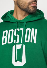Felpa verde con cappuccio che presenta "BOSTON" e il numero "0" in grande testo bianco. Il design include una tasca frontale e cappuccio regolabile con cordini.
