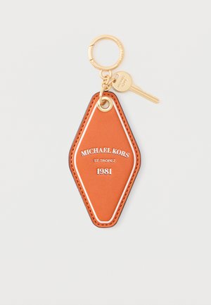 Orange læder-nøglering i diamantform med guldring, lille guldnøgle og teksten "Michael Kors St. Tropez 1981" i midten.