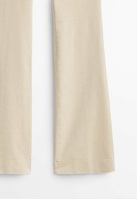 Pantalon en velours côtelé beige avec jambes droites et ridules verticales visibles, présenté sur un fond blanc uni.