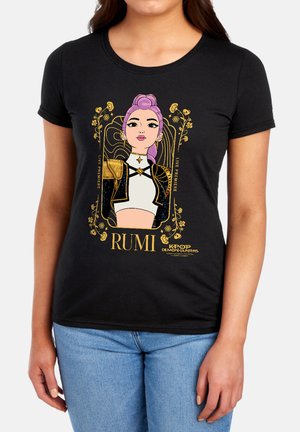 Woman wearing black t-shirt with illustrated female character with purple hair, gold floral frame, and text "RUMI" and "KPOP Demon Hunters."