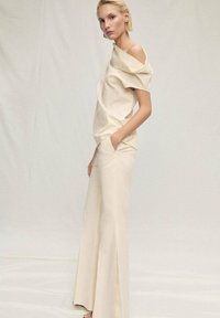Beige off-shoulder top with textured fabric paired with wide-leg pants, both featuring a smooth finish and a relaxed fit, shown against a neutral backdrop.