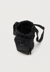 Kompaktowa czarna torba na ramię z nylonu z regulowanym paskiem, przednią kieszenią na zamek i górnym otwarciem z ściągaczem.