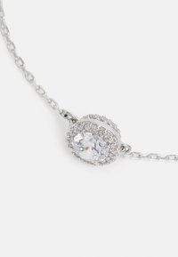 Silberne Kettenhalskette mit einem zentralen ovalen Kristall, umgeben von kleineren Steinen, die eine polierte Oberfläche und aufwendige Details zeigt.