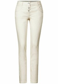 Kremowe, dopasowane spodnie wykonane z elastycznej tkaniny. Posiadają cztery kieszenie oraz zapięcie na trzy guziki z metalicznymi dodatkami.