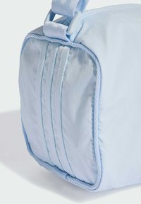 Světlomodrá látková taška s měkkou texturou, s pevnou strukturou, šitými akcenty a splétanou rukojetí pro snadné nošení.