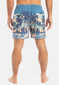 Blaue Badeshorts mit einem Muster aus Palmen und Sonnenuntergang. Leichter Stoff, elastischem Bund, Gesäßtasche mit Druckknopfverschluss.