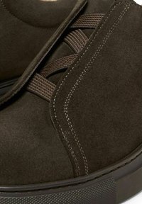 Dunkelbraune Wildlederschuhe mit einem eleganten Design, strukturierter Oberfläche und markanten Nähten entlang der Seite und des Schnürbereichs.