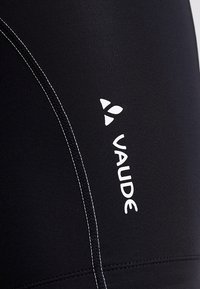 Shorts de vélo noirs avec des coutures blanches. Présente un logo "VAUDE" blanc bien visible et une texture lisse et extensible.