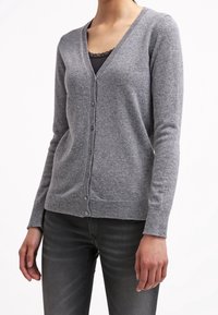 Grå cardigan i mjukt material, med v-ringning, långa ärmar och knäppning fram. Texturerat tyg med en figurnära passform.