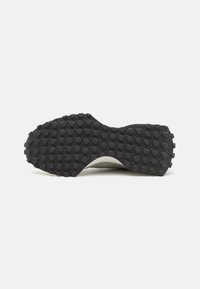 Black rubber outsole with textured surface featuring raised circular patterns, designed for traction and durability.