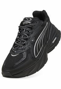 Pantof sportiv negru din plasă și piele sintetică cu accente albe, design curbat, vârf rotund și talpă texturată cu logo de marcă.