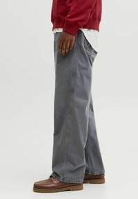 Løst siddende grå bukser lavet af bomuldsblanding, med lige ben, sidelomme og diskret stikning. Sættet er parret med brune loafers.