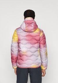 Μπουφάν με επένδυση και μοτίβο σε αποχρώσεις ροζ, μωβ και κίτρινο. Διαθέτει κουκούλα, κυματιστή ραμμένη υφή και ελαστικά μανίκια.