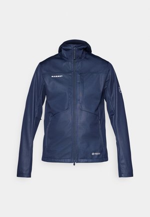 Navy softshell jacket with a high collar and full front zipper. Features zippered pockets, logo detailing, and a lightweight, smooth texture.