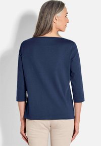 Marineblaues Oberteil mit Dreiviertelärmeln, entspanntem Schnitt und rundem Ausschnitt. Hergestellt aus glattem Stoff und mit einem schlichten Design.